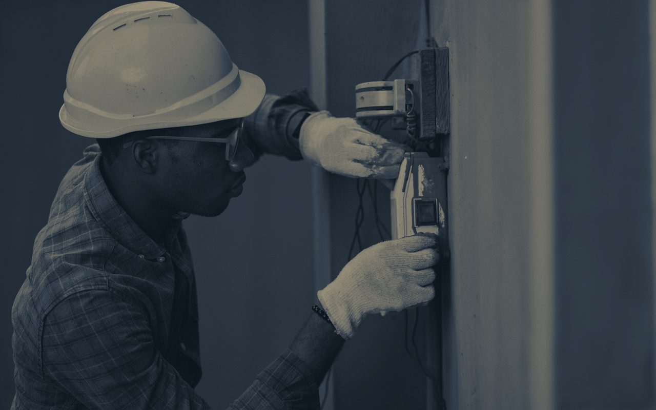 Technician in a hard hat servicing equipment on a residential job